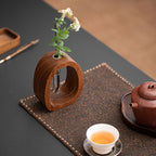 Tea set with wooden vase, teapot, and cup on a dark surface