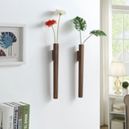 Two wall-mounted vases with plants and flowers in a home setting.