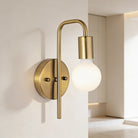 Gold wall-mounted light fixture with a white bulb on a neutral background