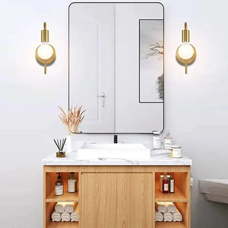 Bathroom vanity with mirror, lights, and various items on a white wall.