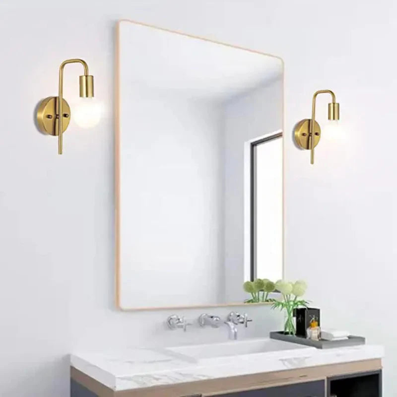 Bathroom vanity with a large mirror, gold wall sconces, and decorative elements.