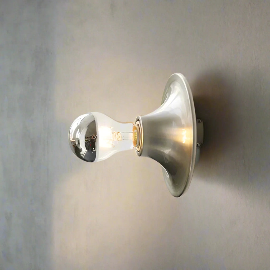 Wall-mounted light fixture with a clear glass shade on a neutral background