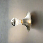 Wall-mounted light fixture with a clear glass shade on a neutral background