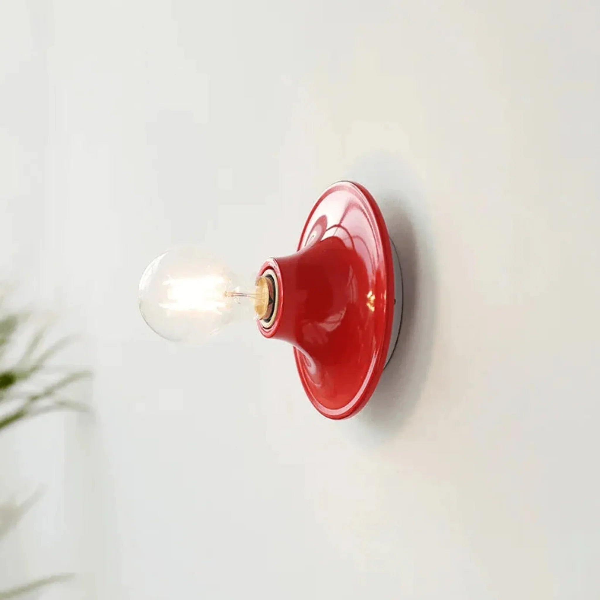 Red wall sconce with a light bulb on a white wall