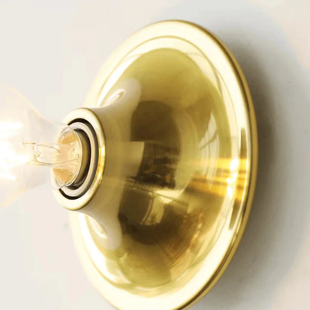 Gold wall sconce with a light bulb on a white background