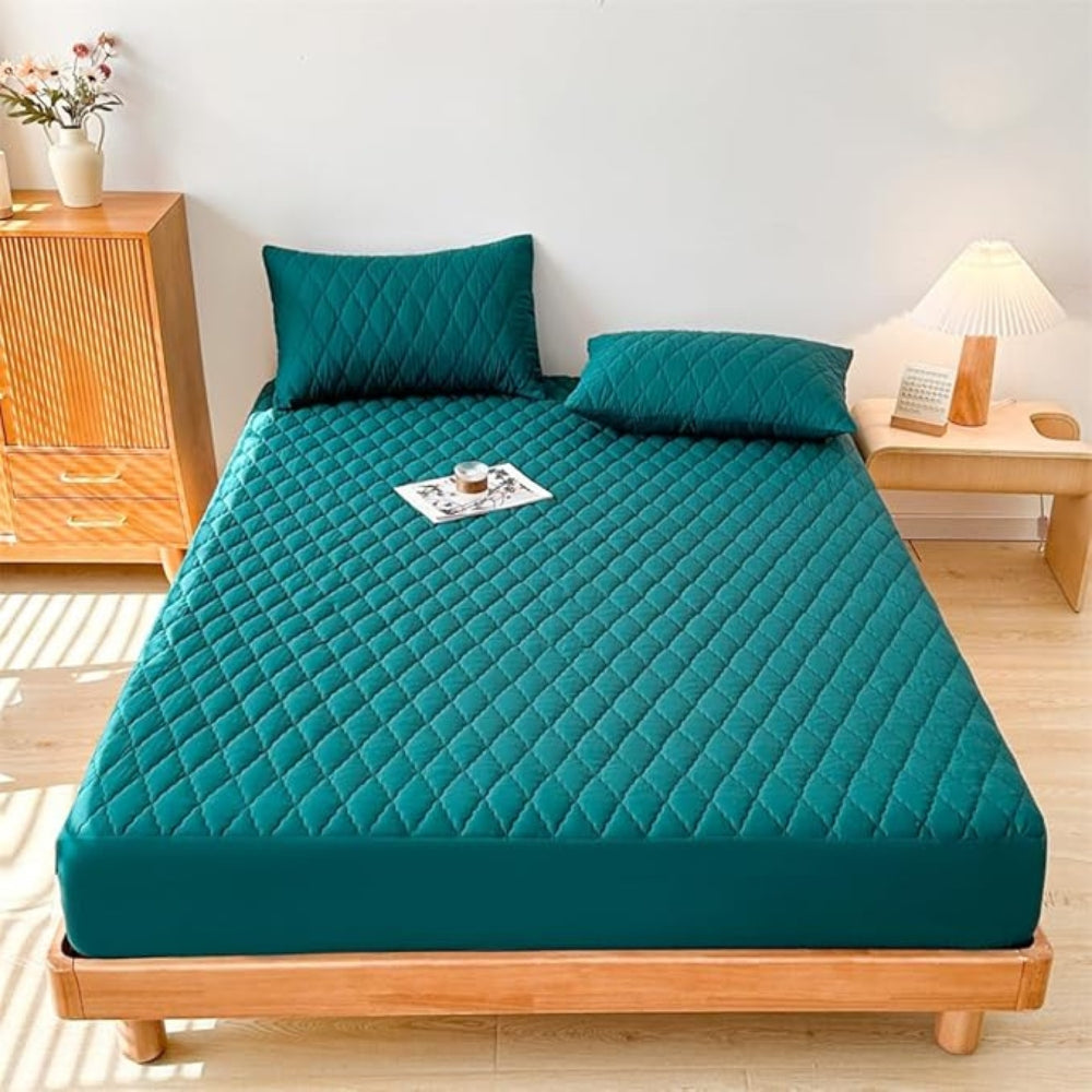 Teal mattress cover on a bed in a bedroom setting with wooden furniture and decor.
