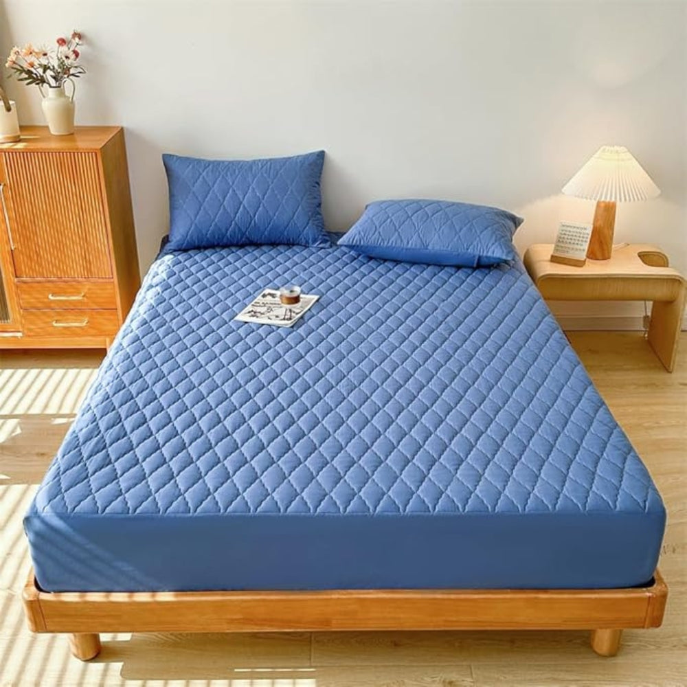 Blue mattress cover on a bed in a bedroom setting with wooden furniture and decor.