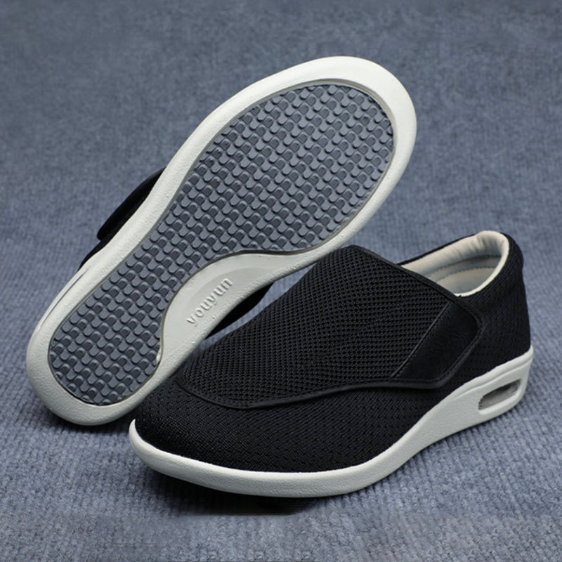 Black slip-on shoes with white soles on a gray background