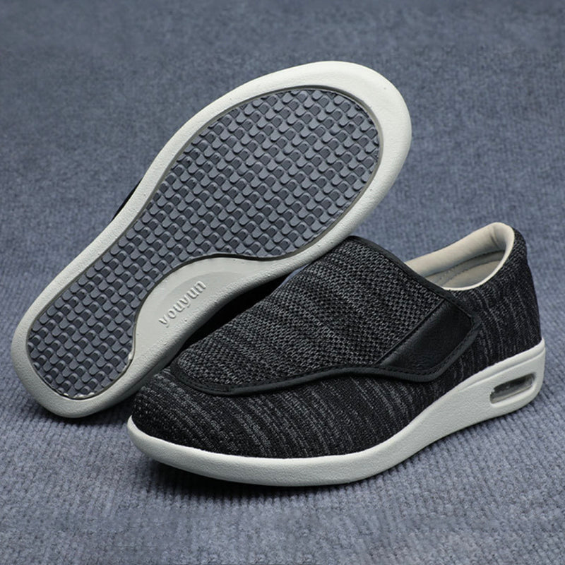 Black slip-on shoes with white soles on a gray textured background