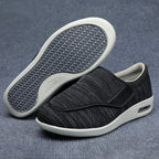 Black slip-on shoes with white soles on a gray textured background