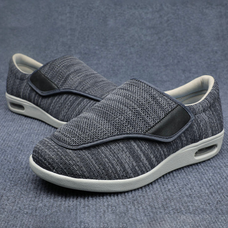 Pair of gray slip-on shoes with velcro straps on a textured gray background