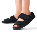 Black open-toe sandals worn by a person on a white background