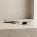 Clear glass straw with black sleeve on a light stone surface