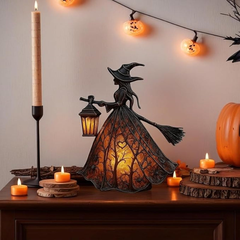 Decorative Halloween witch lamp with candles and pumpkins on a table.