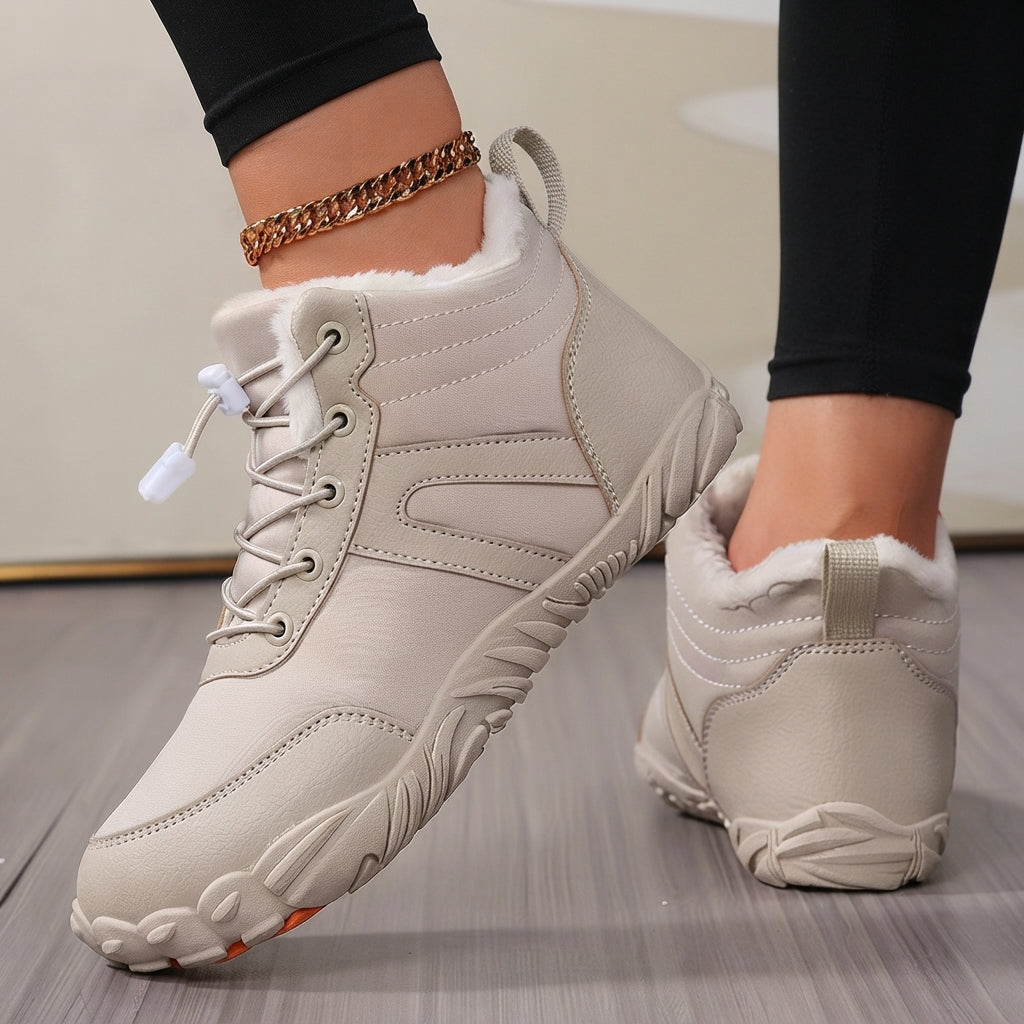 A pair of women's mid-calf winter boots in light beige, shown being worn with black leggings. The boots feature a soft white faux-fur lining, lace-up front, and textured soles, set against a neutral indoor background.