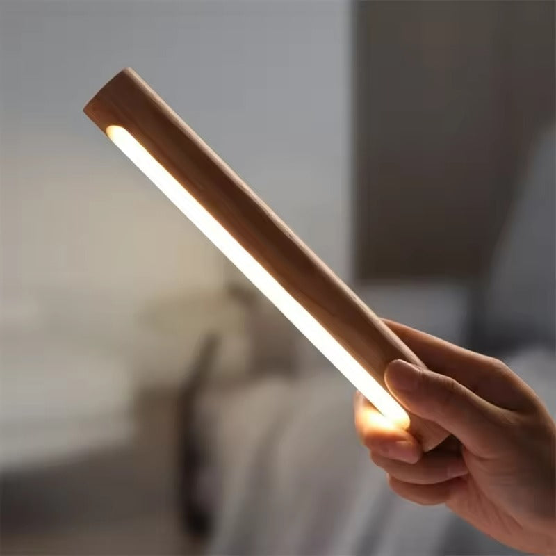 Hand holding a cylindrical light source with a blurred indoor background