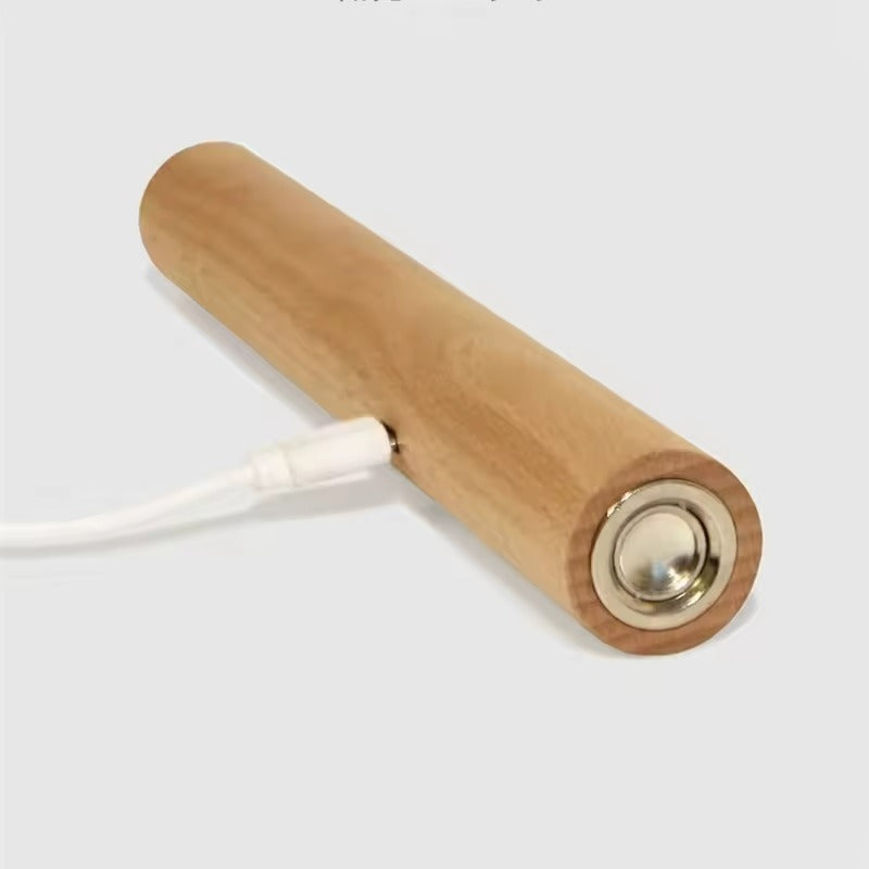 Wooden cylindrical device with a white cable on a light gray background
