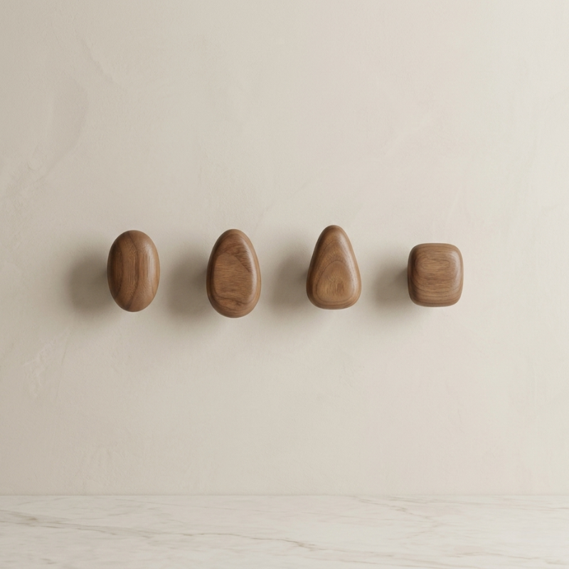 Four wooden wall hooks of different shapes on a beige background