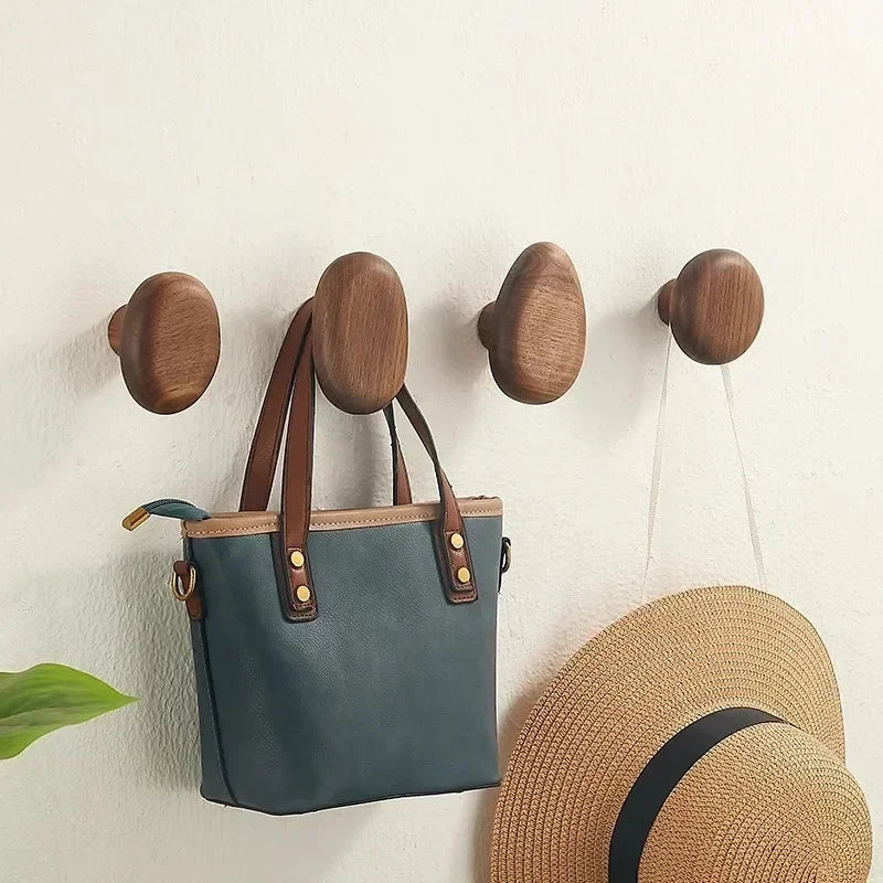 Wooden wall hooks with a blue bag and straw hat on a light background