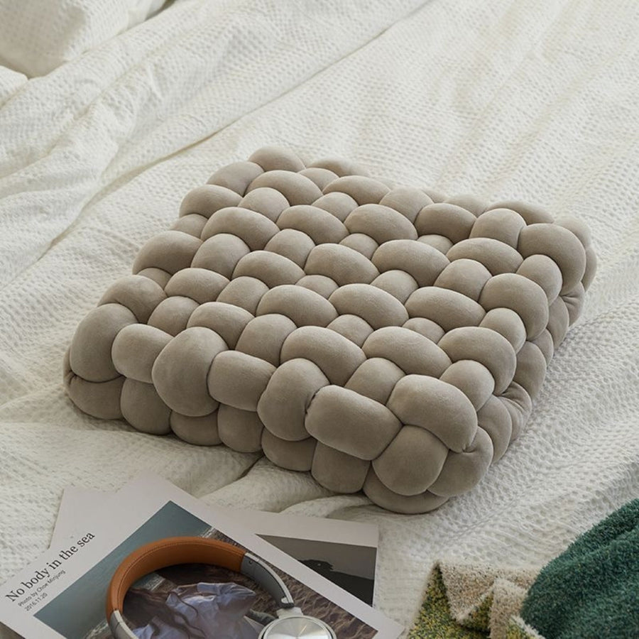 Textured pillow on a bed with magazines underneath