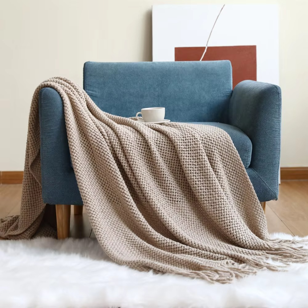 Blue armchair with a beige blanket draped over it in a cozy living room setting.