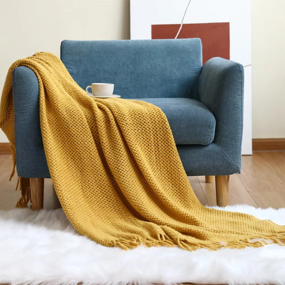 Blue armchair with a yellow blanket draped over it in a cozy room.