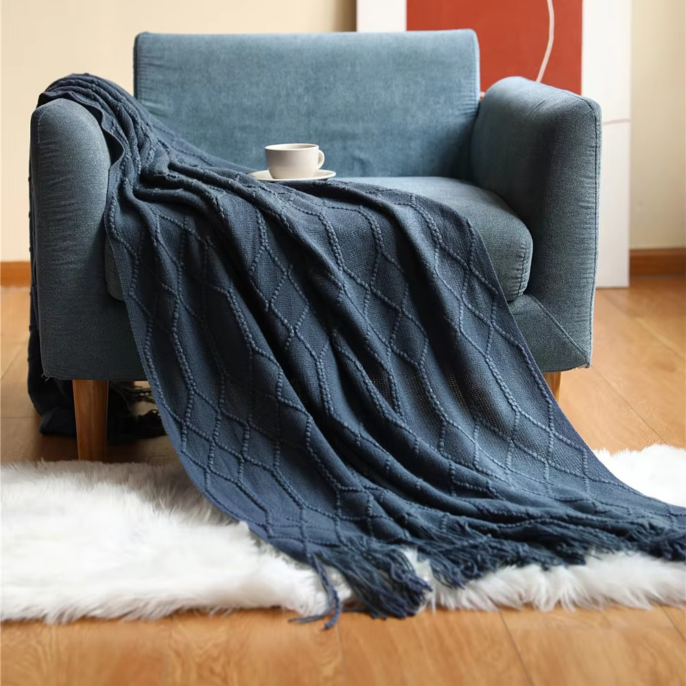 Blue textured blanket draped over a chair with a small table on a wooden floor.
