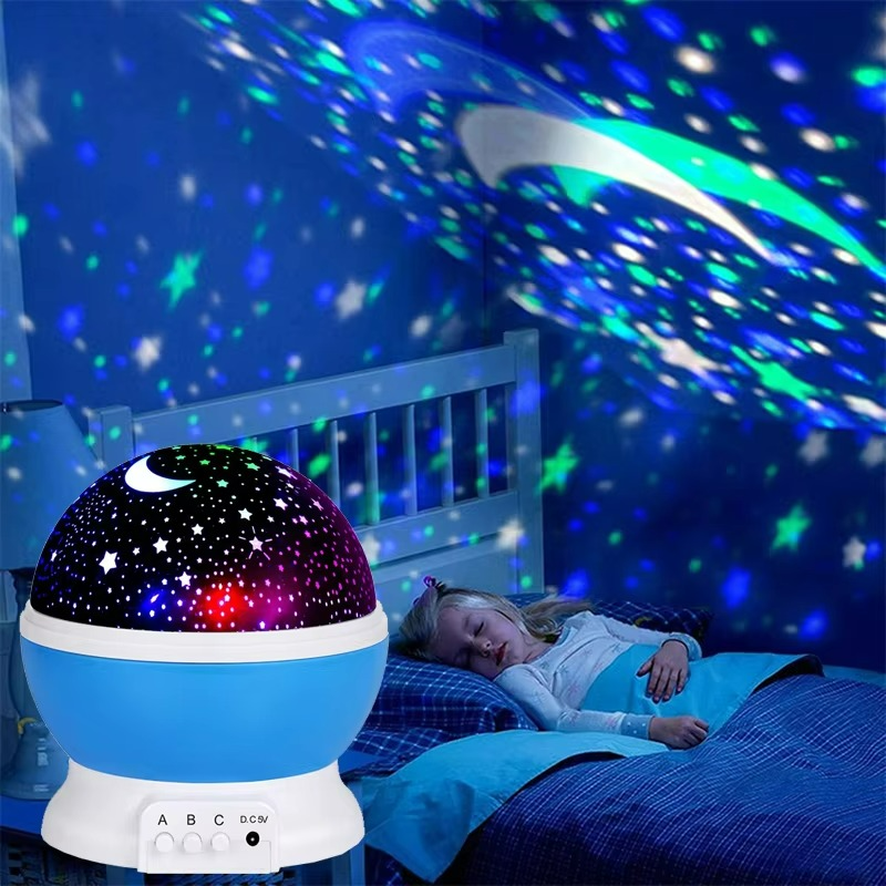 Child lying in bed with a starry night light projector casting colorful patterns on the ceiling.