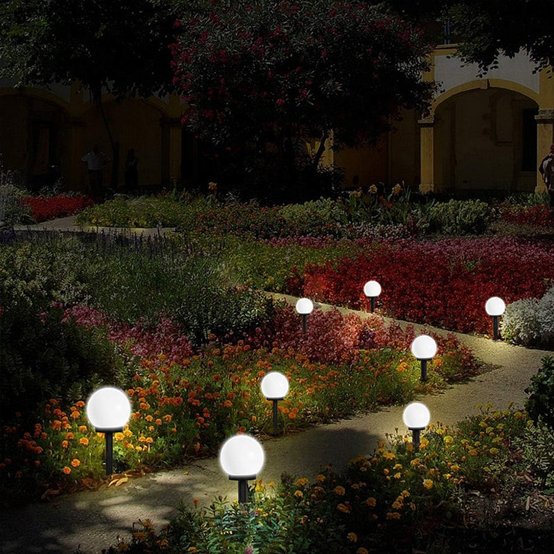 Garden pathway illuminated by decorative outdoor lights at night.