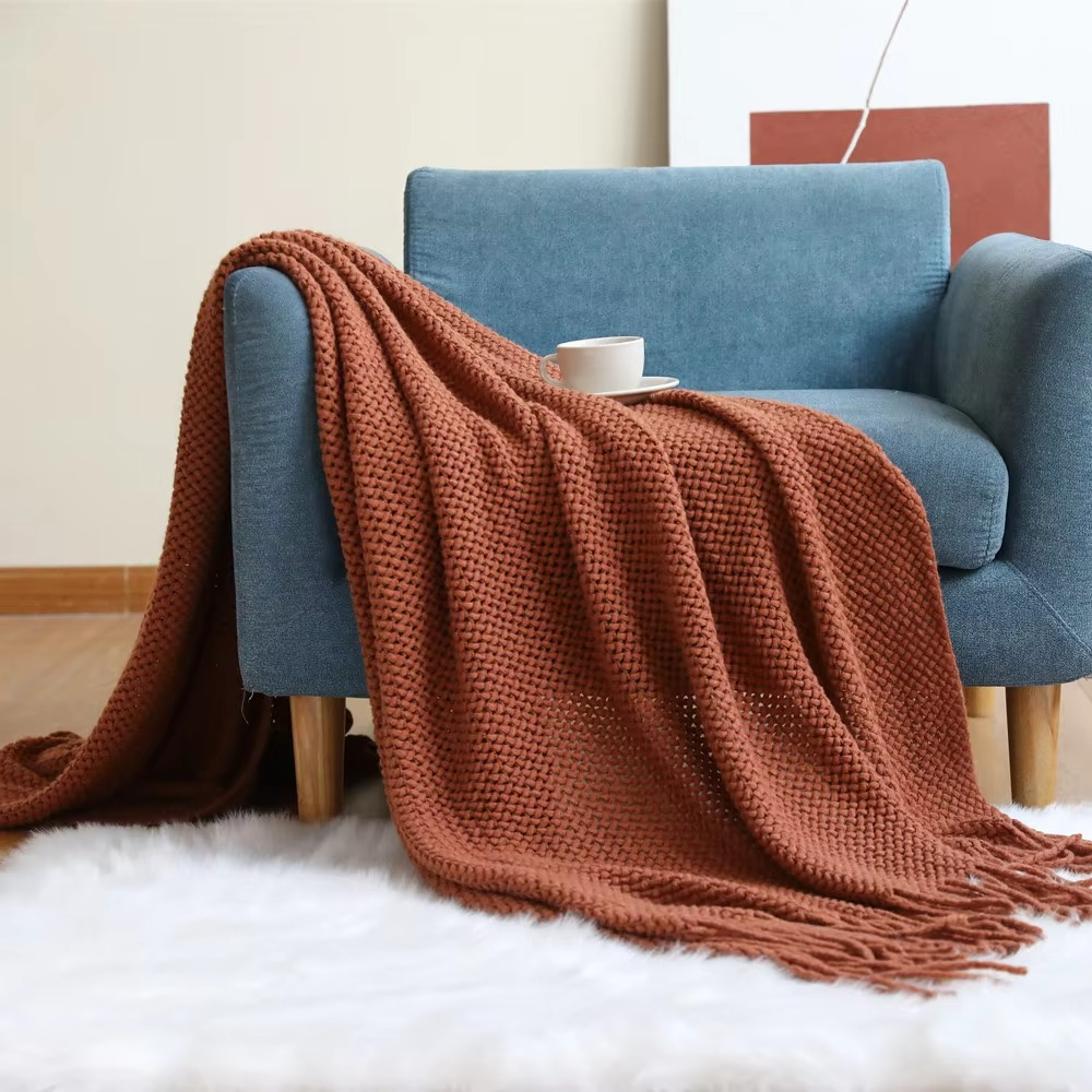 Brown blanket draped over a blue armchair with a white rug underneath