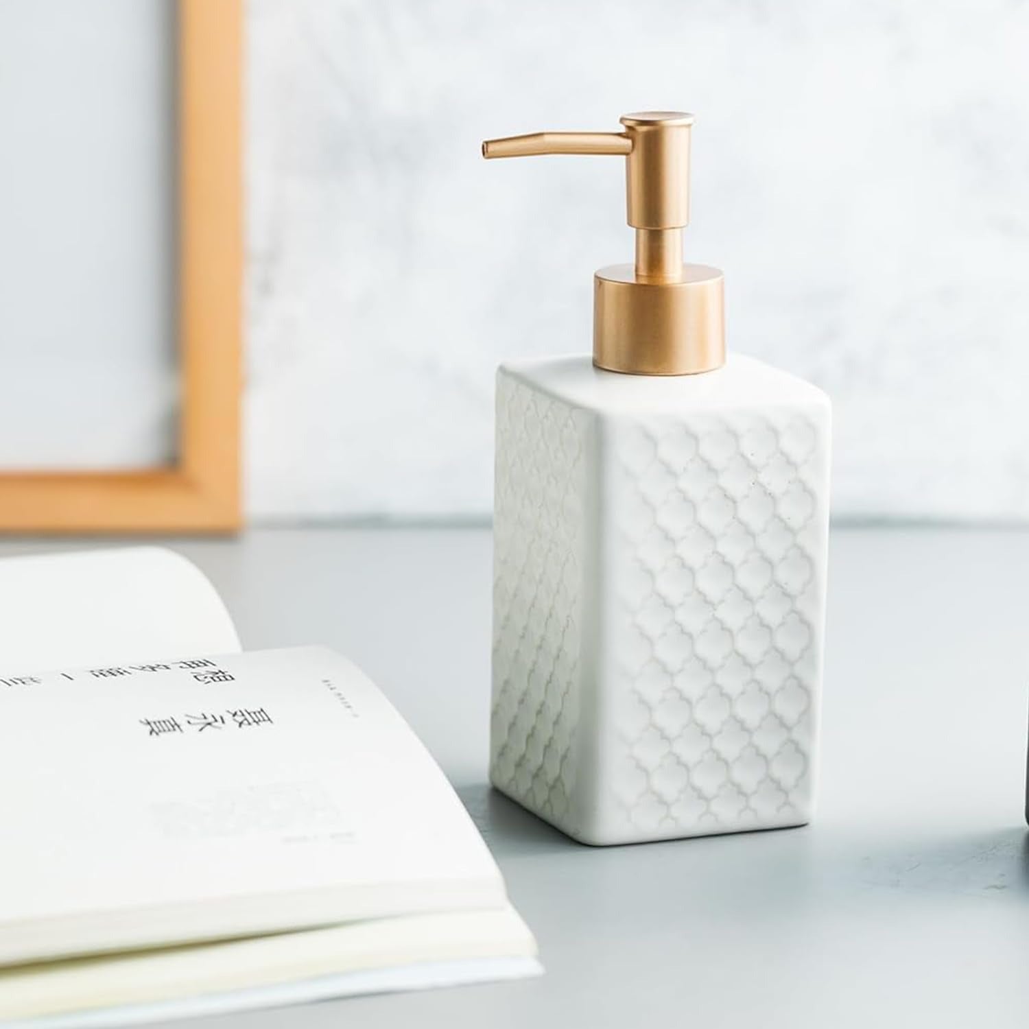 White soap dispenser with gold pump on a light surface
