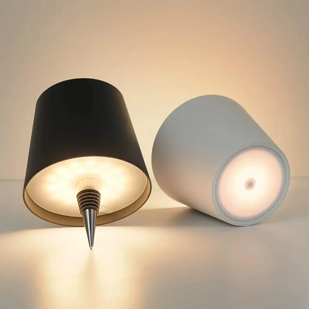 Two cylindrical lamps, one black and one white, on a neutral background.