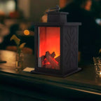 Decorative lantern with glowing interior resembling a fireplace on a table.