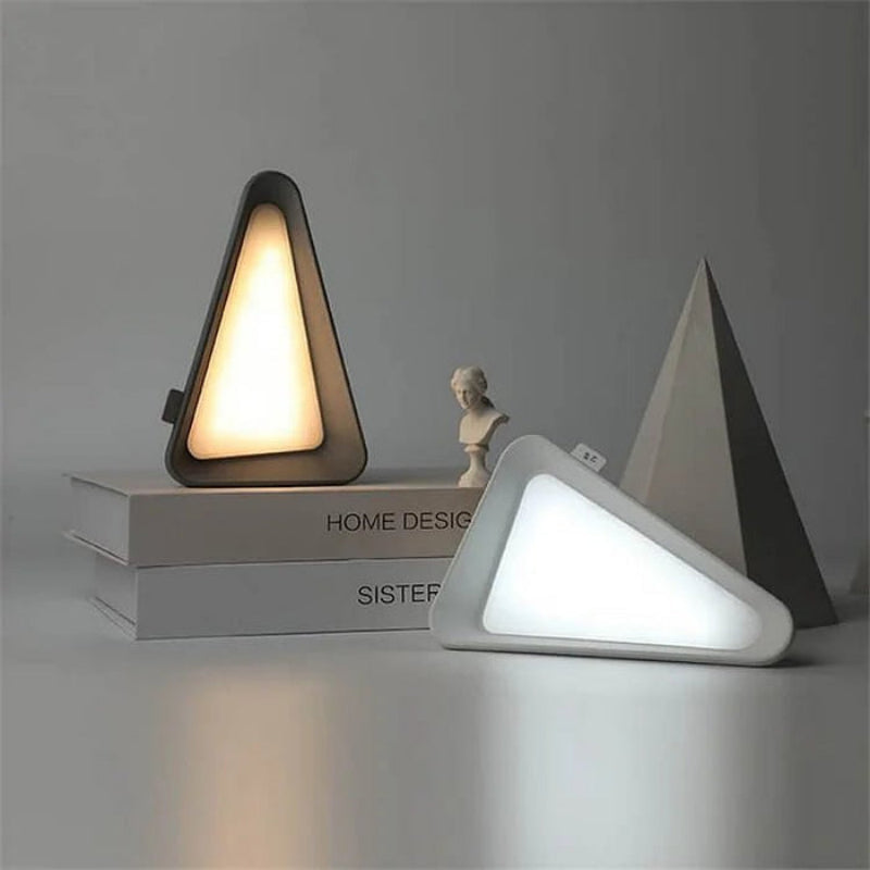 Two triangular table lamps on a gray surface with a neutral background
