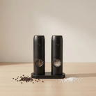 Black salt and pepper shakers on a beige surface with a neutral background