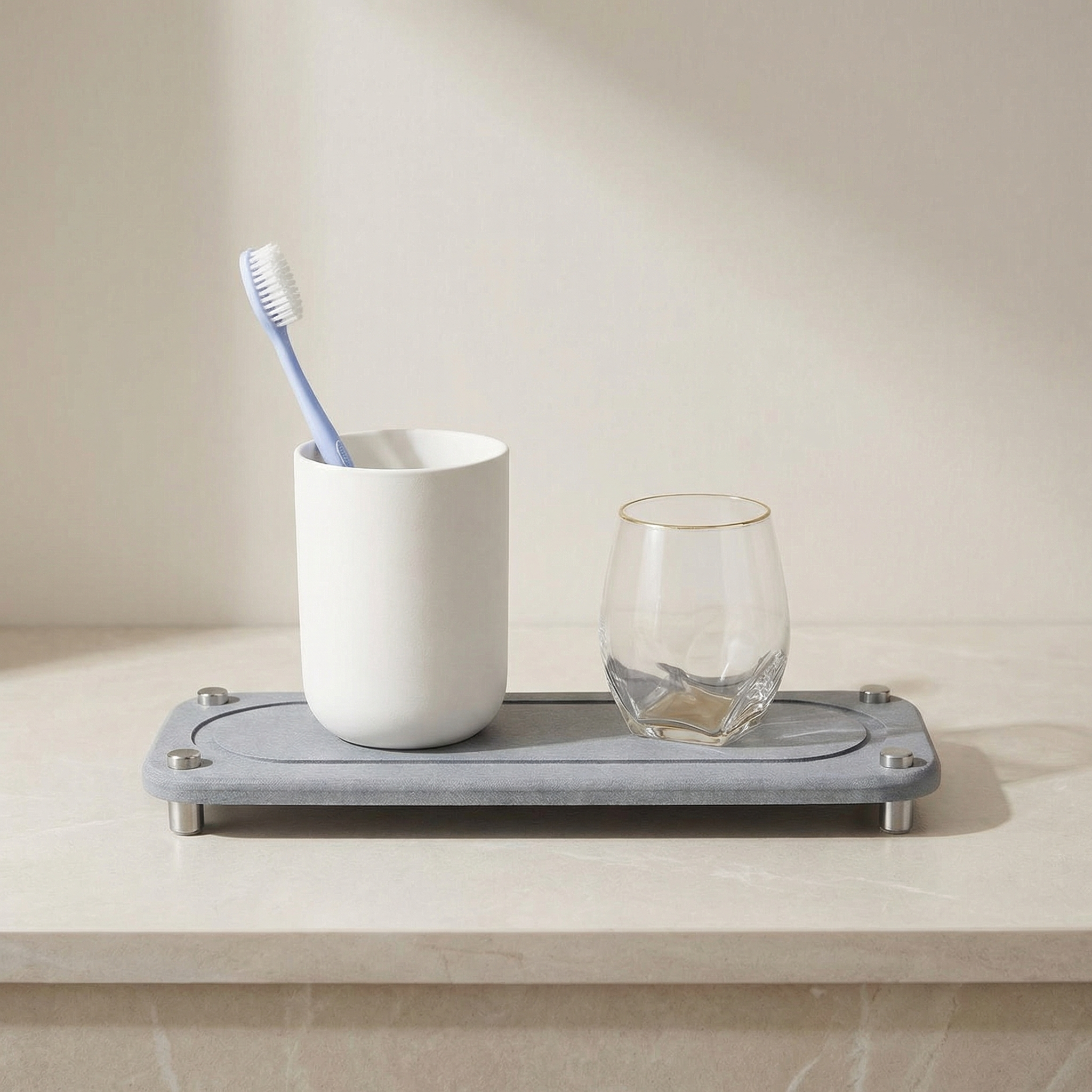 Gray tray with a white cup, toothbrush, and clear glass on a beige surface
