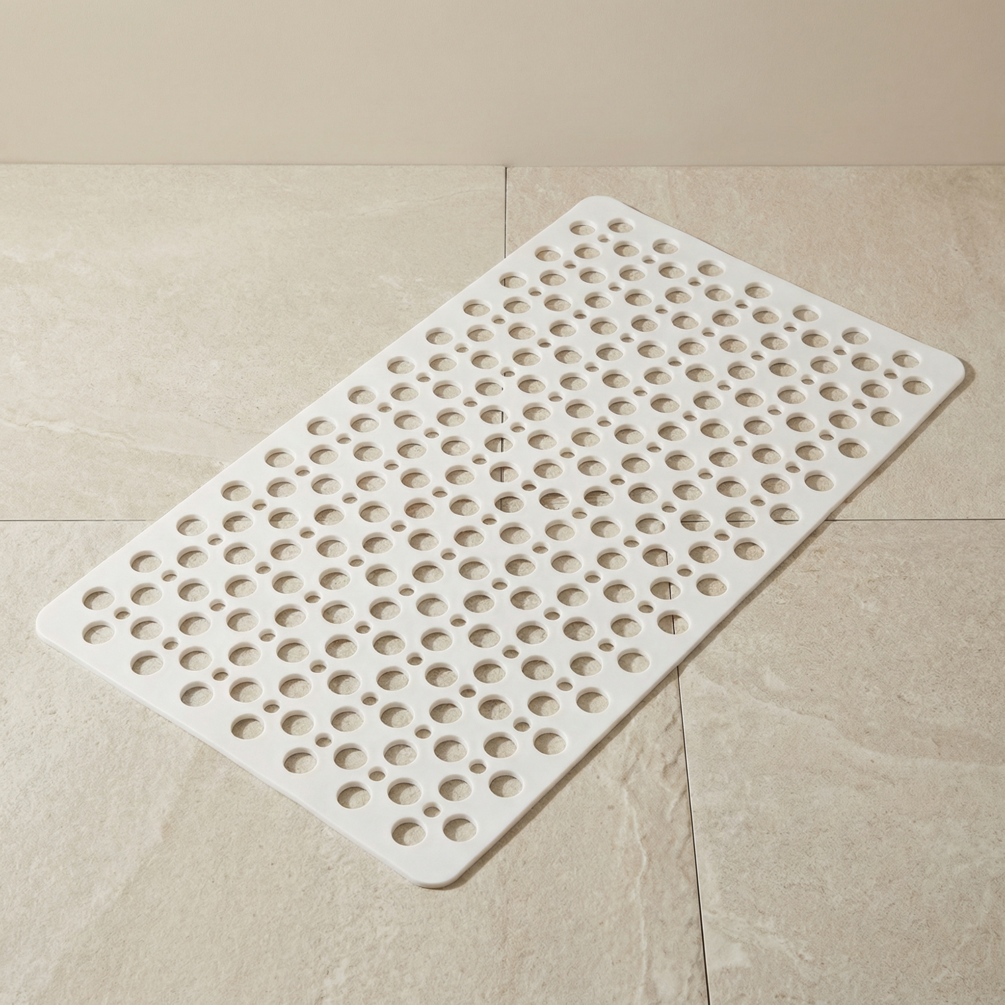 White textured bath mat on a beige tiled floor