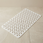 White textured bath mat on a beige tiled floor