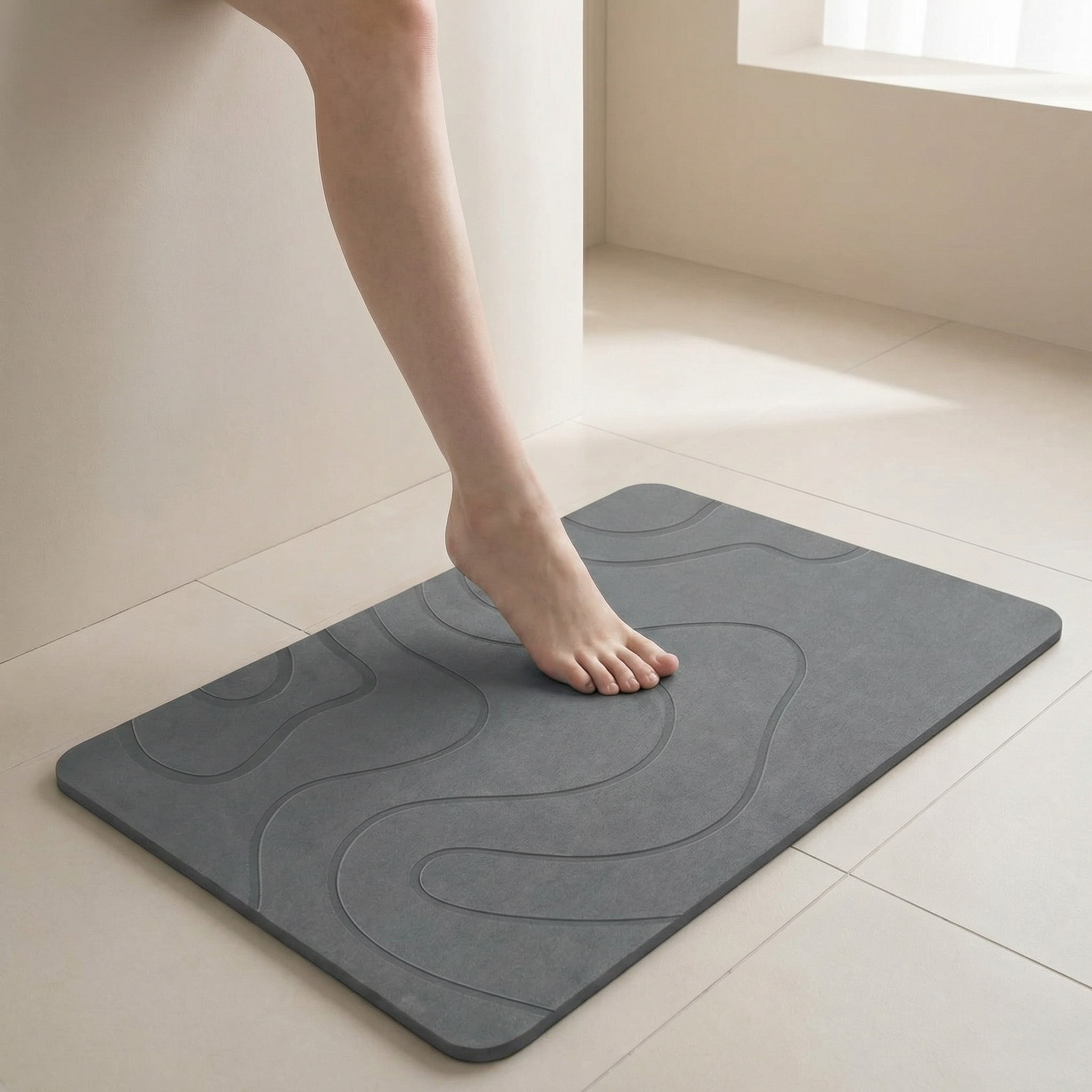 Person stepping onto a textured gray bath mat in a bathroom.