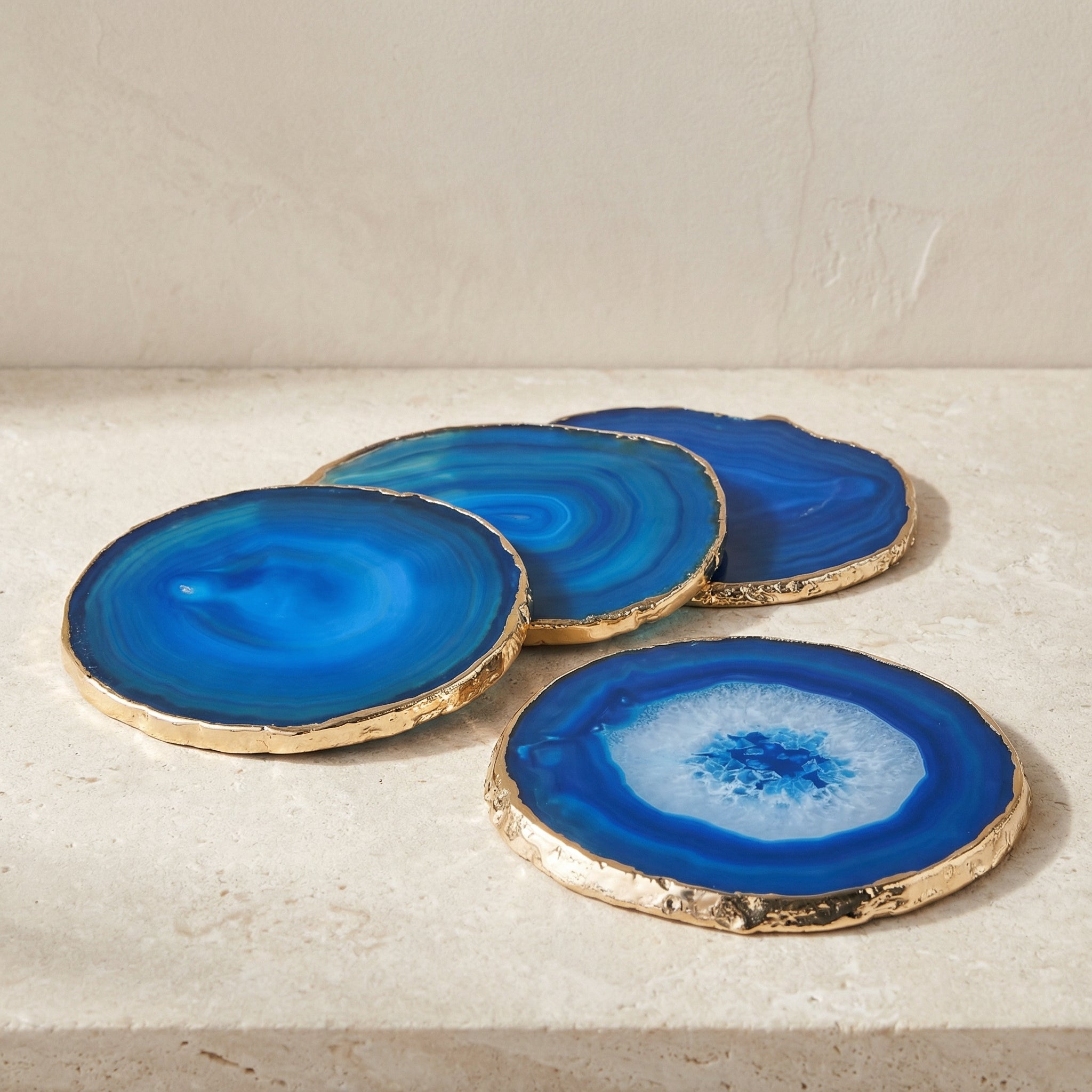 Set of blue agate coasters with gold edges on a light surface.