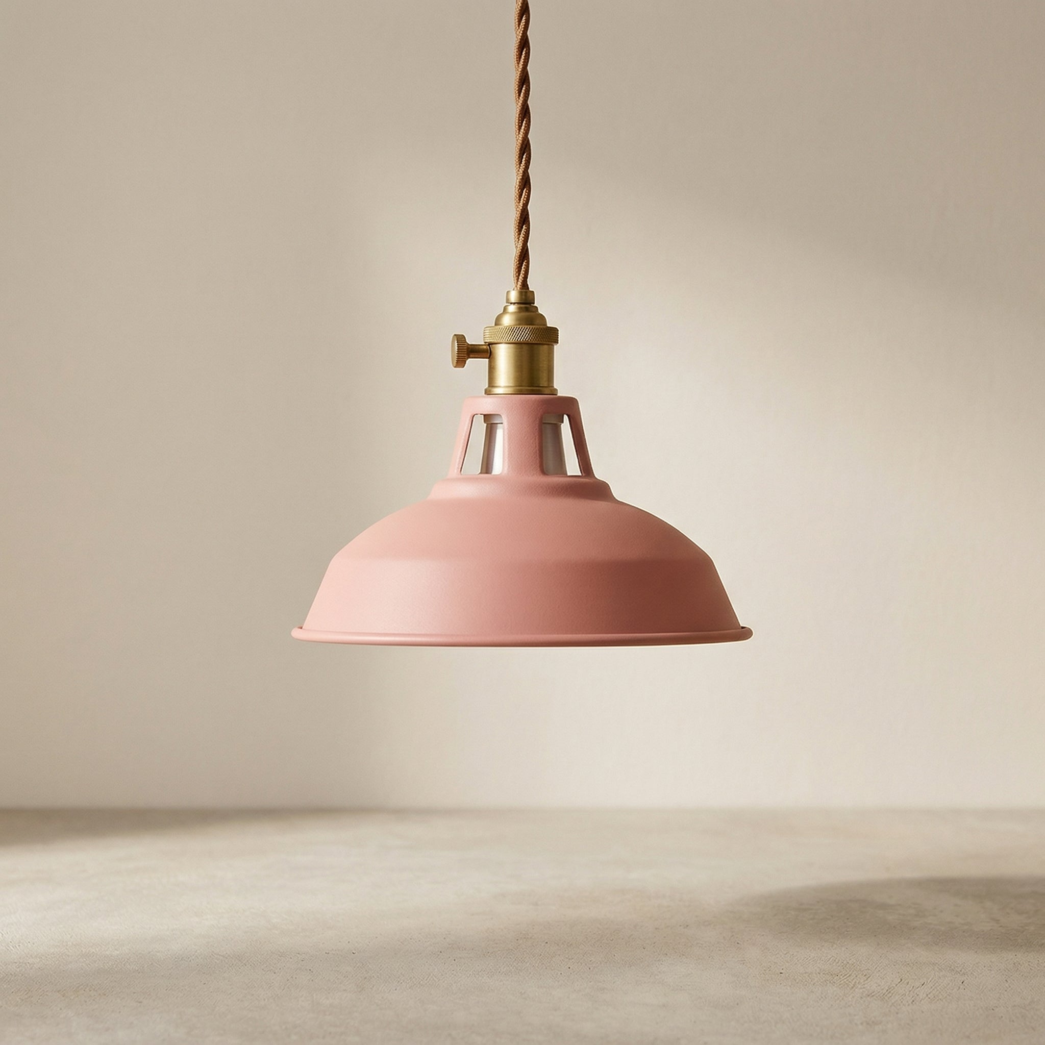 Pink pendant light with brass fitting on a neutral background
