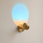 Wall-mounted light fixture with a gradient glass shade on a plain wall.