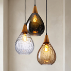 Three glass pendant lights with wooden accents on a neutral background