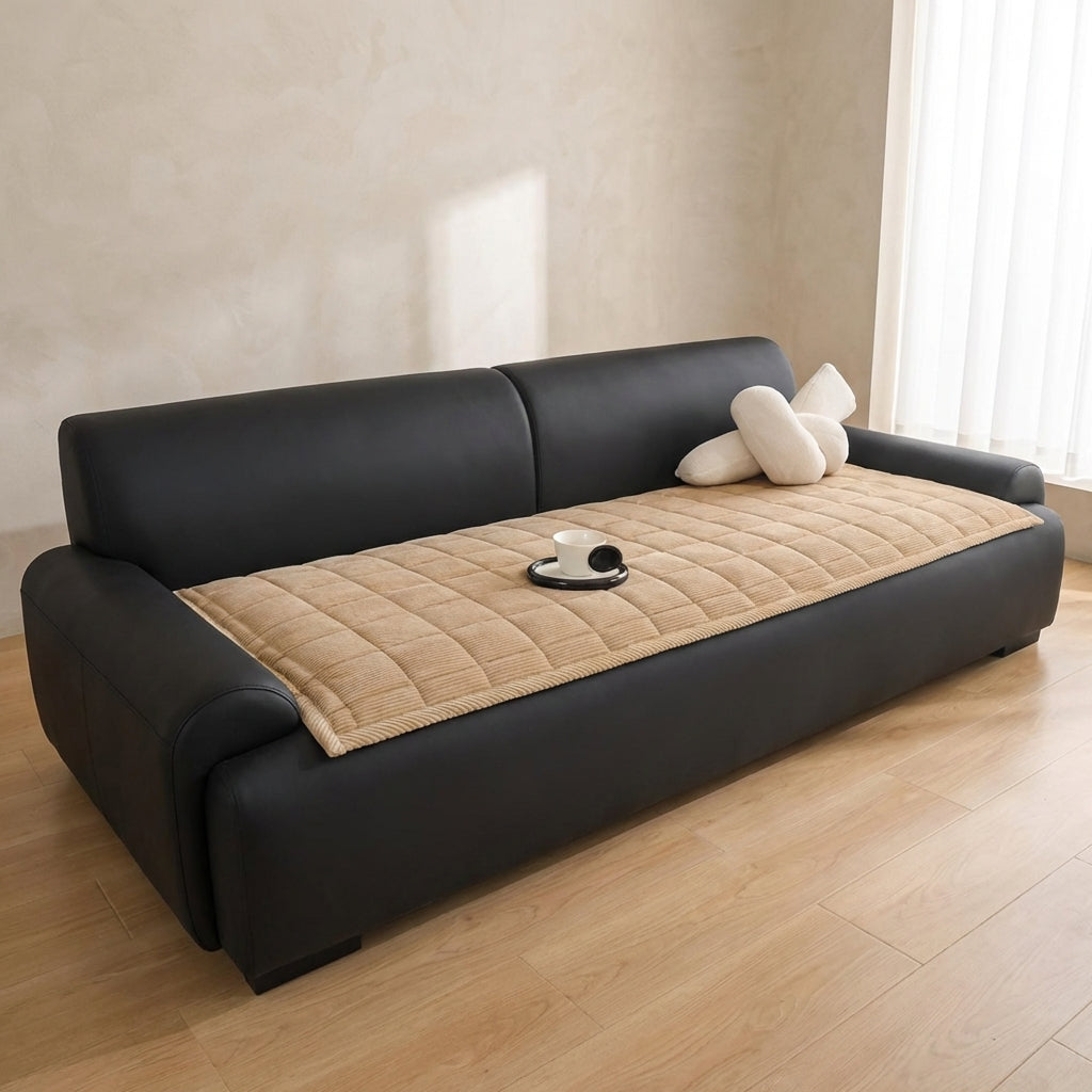 Black sofa with beige cushion on a wooden floor in a room with light-colored walls.