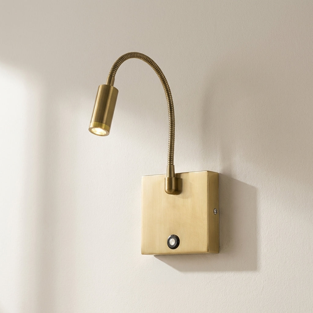Brass wall-mounted reading light with flexible arm on a beige wall.