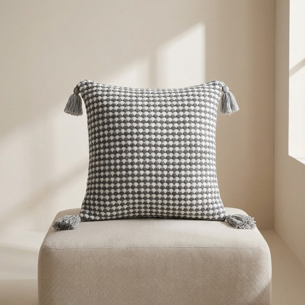 Decorative pillow with geometric pattern and tassels on a beige chair.