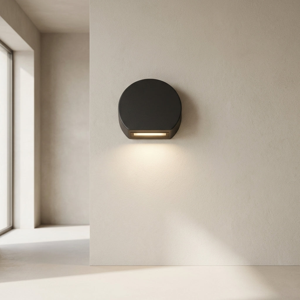 Modern wall-mounted light fixture on a neutral wall next to a window.
