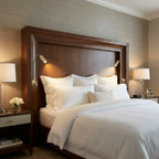 Neatly made bed with white bedding in a bedroom setting.
