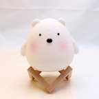 White bear-shaped object on a small wooden stand against a light background