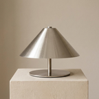 Silver table lamp on a beige pedestal against a beige background